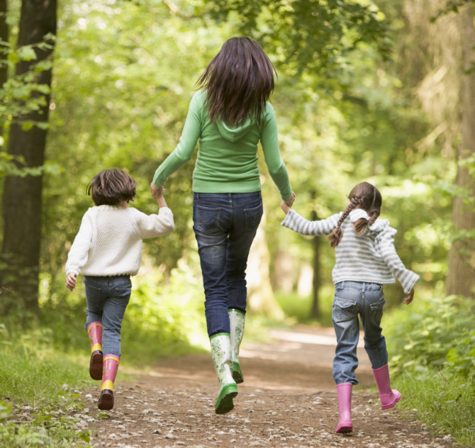Mom holding hands with daughters on trail